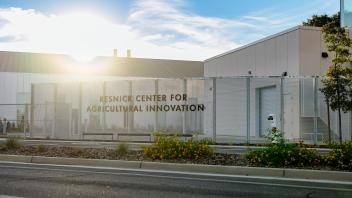 Resnick Agricultural Innovation Center exterior with fence, roadside and bright sun glare